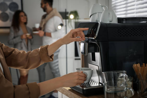 Woman preparing fresh aromatic coffee with modern machine in office, closeup